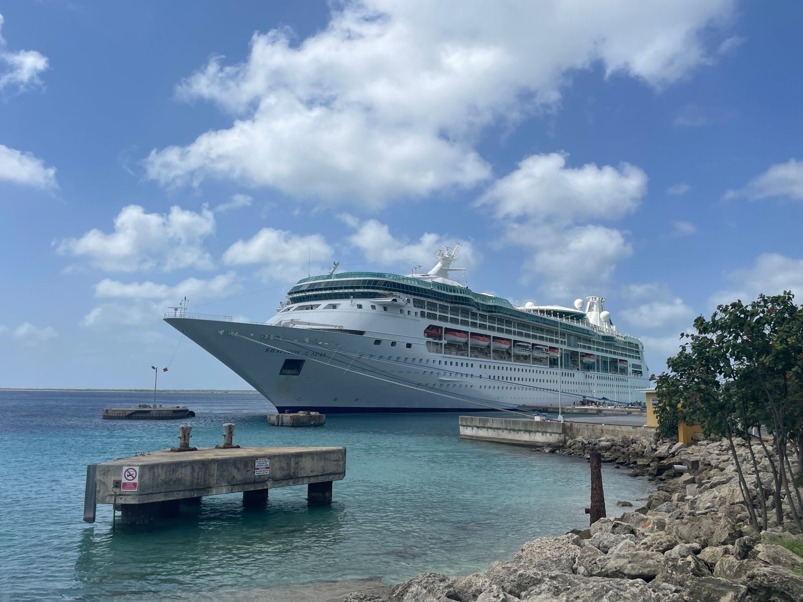 Cruise ship docked in a clear tropical harbor under a bright blue sky