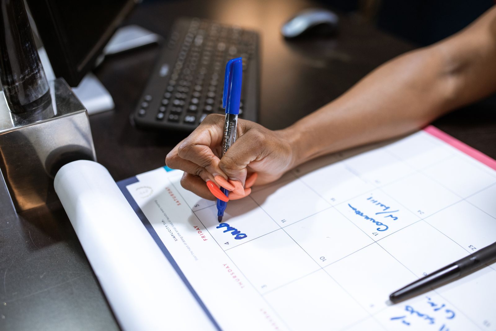 Hand writing notes on a calendar with a blue marker, planning a cruise search by date